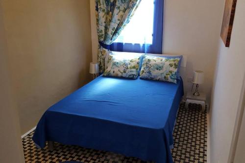 una piccola camera con letto blu e finestra di Fully Air-Conditioned Traditional Maltese House a Żejtun