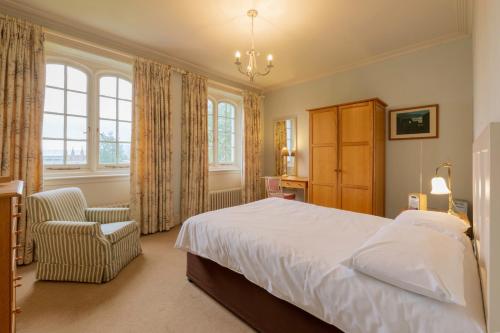 a bedroom with a large bed and a chair at West Dean College in West Dean