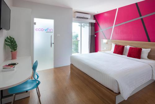 um quarto com uma cama branca e uma parede rosa em Eco Inn Lite Chanthaburi em Chanthaburi