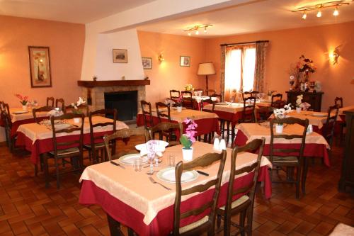 a dining room with tables and chairs and a fireplace at Relais de Frejeroques in Foissac
