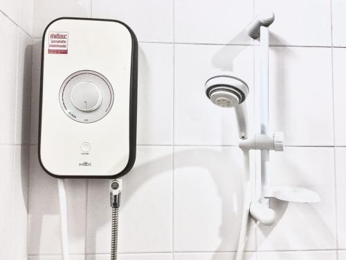 a shower head in a white tiled bathroom at The room Apartment in Surat Thani