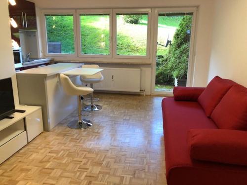 a living room with a red couch and a kitchen at Apartement Zwölferhorn in Sankt Gilgen