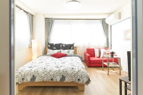 a bedroom with a bed and a red couch at ESPERANZA103 広い綺麗快適高速WiFi in Tokyo