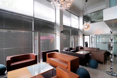 a waiting room with leather chairs and tables and windows at Maniatis Hotel in Sparti