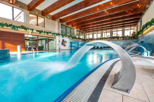 a swimming pool with a slide in a building at Wellness Hotel Diplomat in Rajecké Teplice