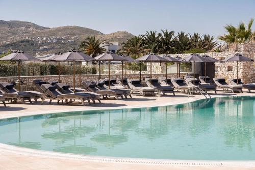 a swimming pool with chairs and umbrellas at Saint Andrea Seaside Resort - Adults Only in Naousa