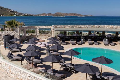 a pool with chairs and umbrellas next to the ocean at Saint Andrea Seaside Resort - Adults Only in Naousa