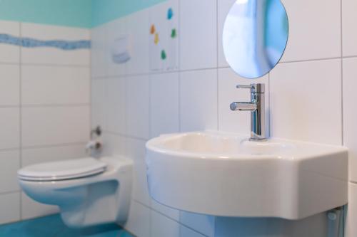 a bathroom with a sink and a toilet and a mirror at Ferienwohnungen Landgasthaus Janshen in Ellscheid
