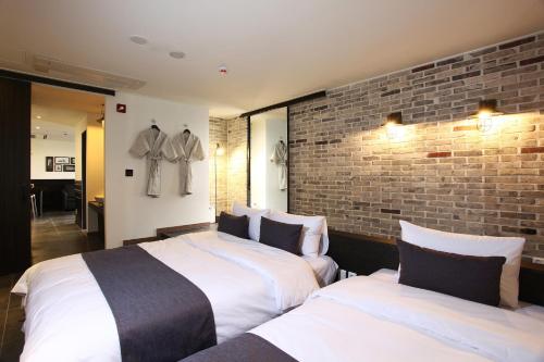 a bedroom with two beds and a brick wall at S& Hotel in Daejeon