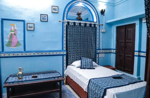 a bedroom with blue walls and a bed and a table at Purn Haveli in Jodhpur