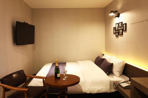 S& Hotel في دايجون: غرفة في الفندق مع سرير وطاولة مع زجاجة من الشمبانيا