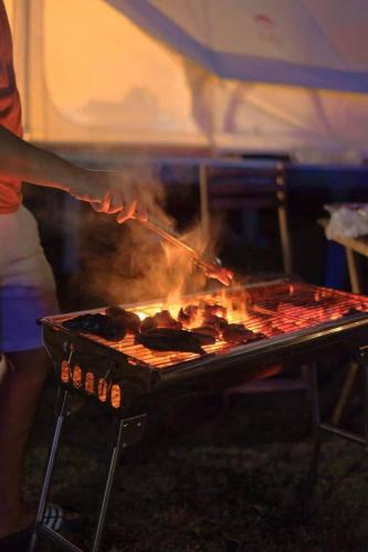 een persoon kookt eten op een grill bij Ozone by บ้านเขาค้อ in Phetchabun