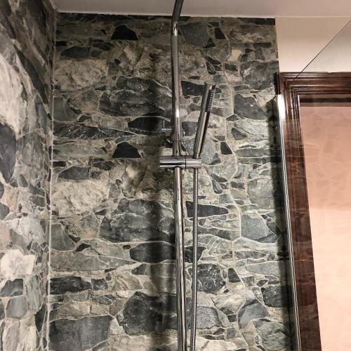 a shower in a bathroom with a stone wall at Los Balcones de Nieda in Cangas de Onís