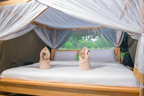 a bed in a tent with two pairs of shoes on it at Fort Murchison Lodge by NATURE LODGES LTD in Pakwach East