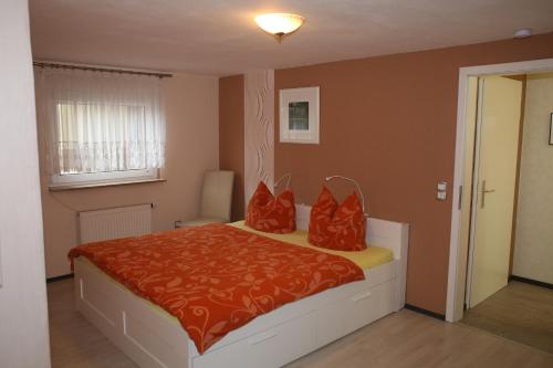 a bedroom with a bed with red pillows on it at Logis Am Park in Dessau
