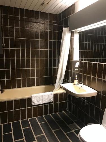 La salle de bains est pourvue de carrelage noir, d'un lavabo et de toilettes. dans l'établissement Villa Grande, à Hadsten Stationsby