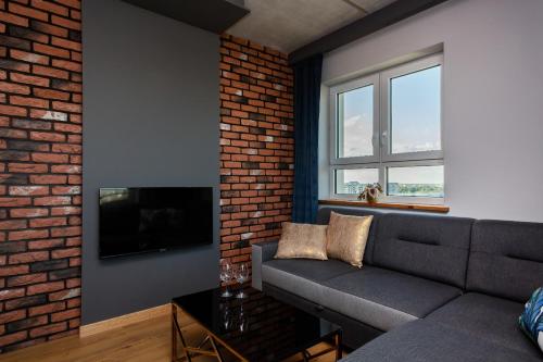a living room with a couch and a brick wall at Apartments Parks of Warsaw by Renters in Warsaw
