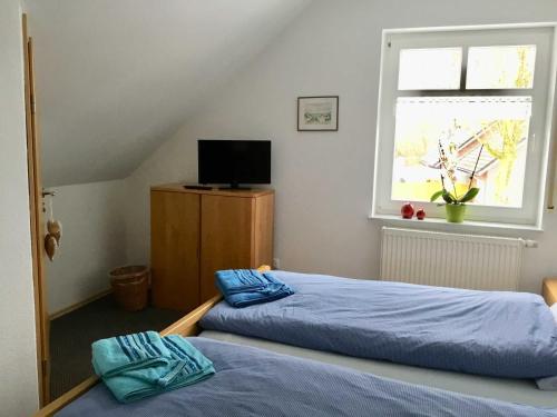 a bedroom with two beds and a television and a window at Ferienwohnung Rossis Nüst, 31516 in Uplengen