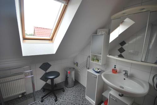 baño con lavabo, espejo y taburete en Ferienwohnung Rossis Nüst, 31516, en Uplengen
