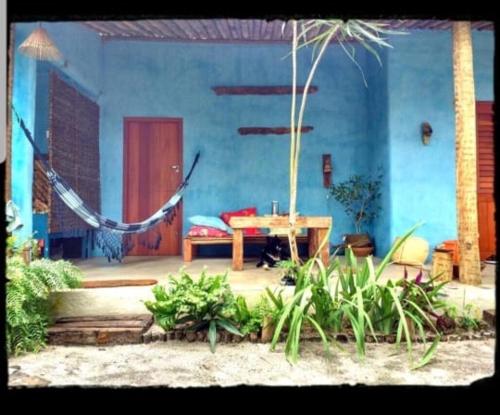 a blue house with a hammock in front of it at Pousada Spa Oasis in Caraíva