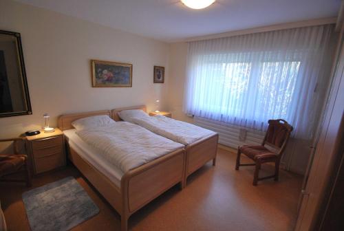 ein Schlafzimmer mit einem Bett, einem Stuhl und einem Fenster in der Unterkunft Ferienhaus Hermann, 35522 in Uplengen