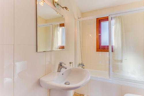 Baño blanco con lavabo y espejo en YupiHome Villa de les Aguiles, en Alcudia