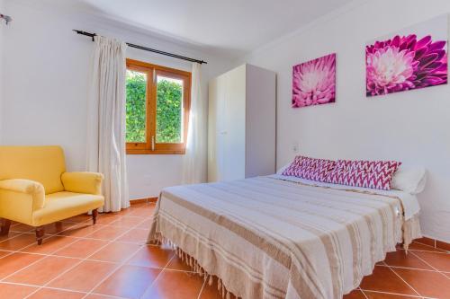 a bedroom with a bed and a chair and a window at YupiHome Villa Ca S'Anglès in Alcudia
