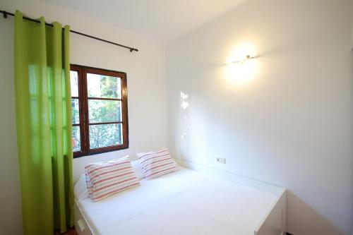 ポータル・ヌースにあるYupiHome Holiday Home Ketyの緑のカーテン付きのベッドが備わる客室です。