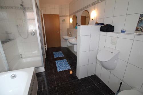 a bathroom with two toilets and a sink and a tub at Ferienwohnung Rossbach, 95061 in Rhauderfehn