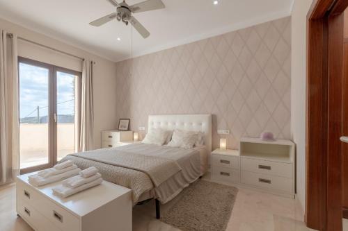 a white bedroom with a bed and a window at YupiHome Villa Es Sequer in Maria de la Salut