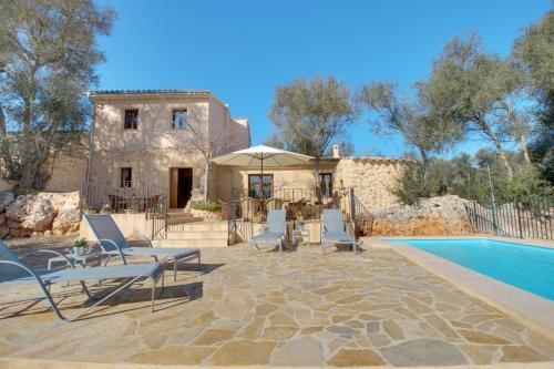 a patio with chairs and a pool and a house at Finca S'Erissal de Costitx in Costitx