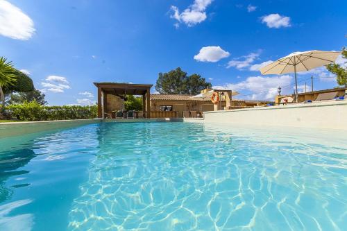 a swimming pool with an umbrella and a house at Finca Sa Reconada de L'Ullastre - Family only in Algaida