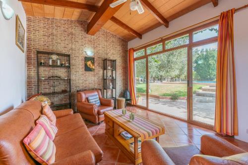 a living room with leather furniture and a large window at Finca Can Lluc in Alaró