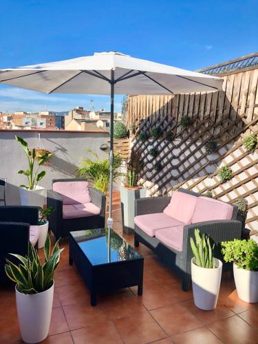 a patio with couches and an umbrella on a roof at Barcelona Fifteen central Aparthotel in Barcelona
