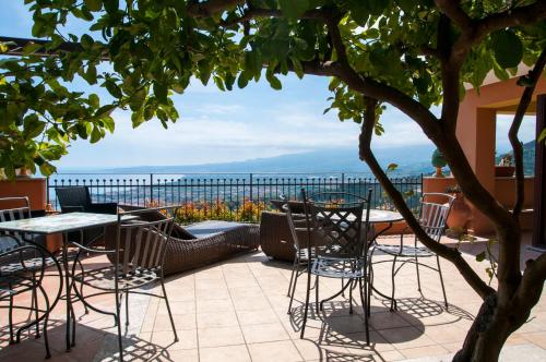 a patio with tables and chairs and a view of the ocean at Villa Le Terrazze Charming Rooms in Taormina