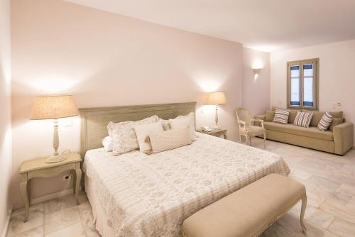 a white bedroom with a bed and a couch at Saint Andrea Seaside Resort - Adults Only in Naousa
