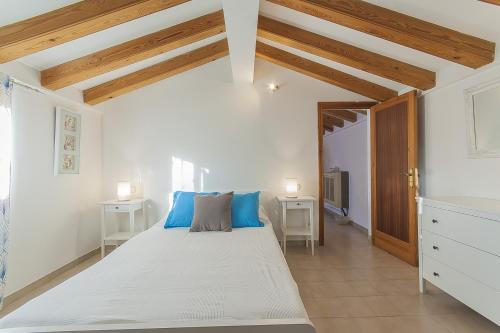 a bedroom with a large white bed with blue pillows at Villa Mª ANTOINETTE in Portals Nous