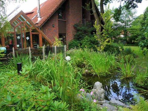 a garden in front of a house with a pond at Ferienwohnung Am Traumgarten, 35646 in Uplengen