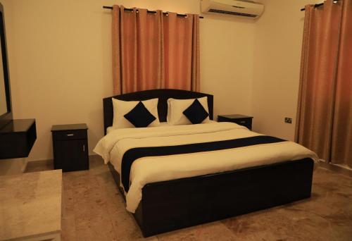 a bedroom with a black and white bed with pillows at Star Emirates Garden Villas Salalah in Salalah