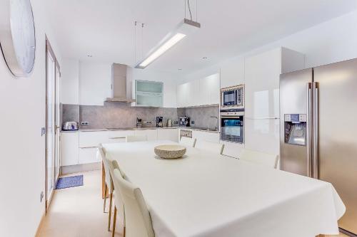 a white kitchen with a white table and chairs at Apartment Ca Na Xisca II in Can Picafort