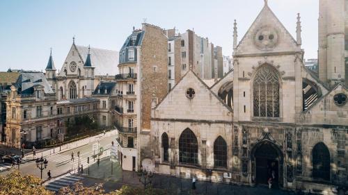 an old church in a city with tall buildings at Hôtel National Des Arts et Métiers in Paris