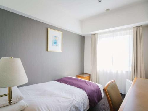 a hotel room with a bed and a window at JR Hotel Clement Uwajima in Uwajima