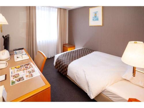 a hotel room with two beds and a desk at JR Hotel Clement Uwajima in Uwajima