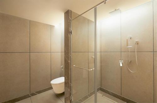 a bathroom with a toilet and a glass shower at The Residency Towers Puducherry in Puducherry