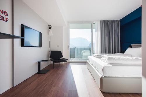 a hotel room with a bed and a chair and a window at HOODY ACTIVE & HAPPINESS HOTEL in Arco