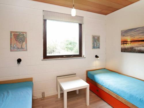 a room with two beds and a table and a window at Holiday Home Brunbjergvej in Nørby
