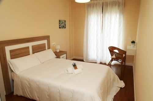 a bedroom with a white bed and a chair and a window at Apartamento Turistico Puente Romano P4 bajo C in Salamanca