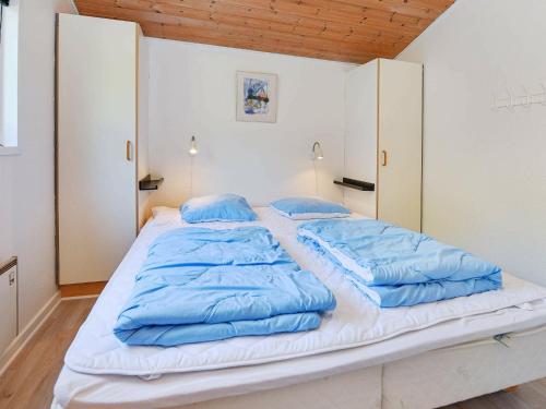 OksbølにあるFour-Bedroom Holiday home in Oksbøl 18の大型ベッド(上に青い枕付)