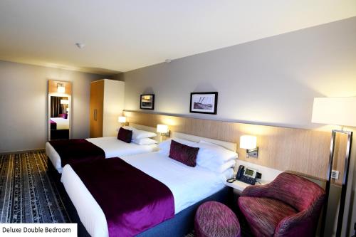 um quarto de hotel com duas camas e duas cadeiras em Lancaster Hotel em Uxbridge