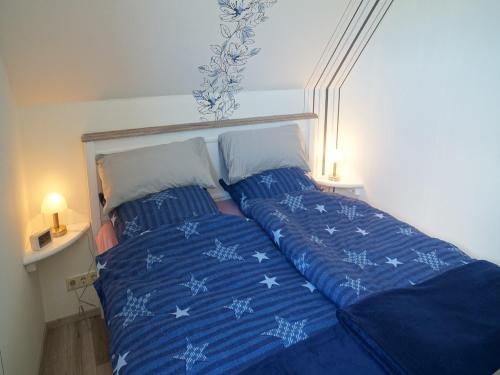 a bed with blue comforter and two pillows at Ferienwohnung an der Au in Taarstedt